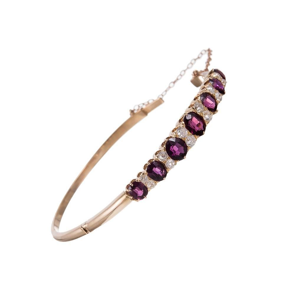 An ever-popular style with antique jewelry enthusiasts, this English carved bangle bracelet is rendered in 18 carat gold and decorated with rhodolite and diamonds, 6 carats and 1.25 carats each respectively. The style lends itself to daily rare with