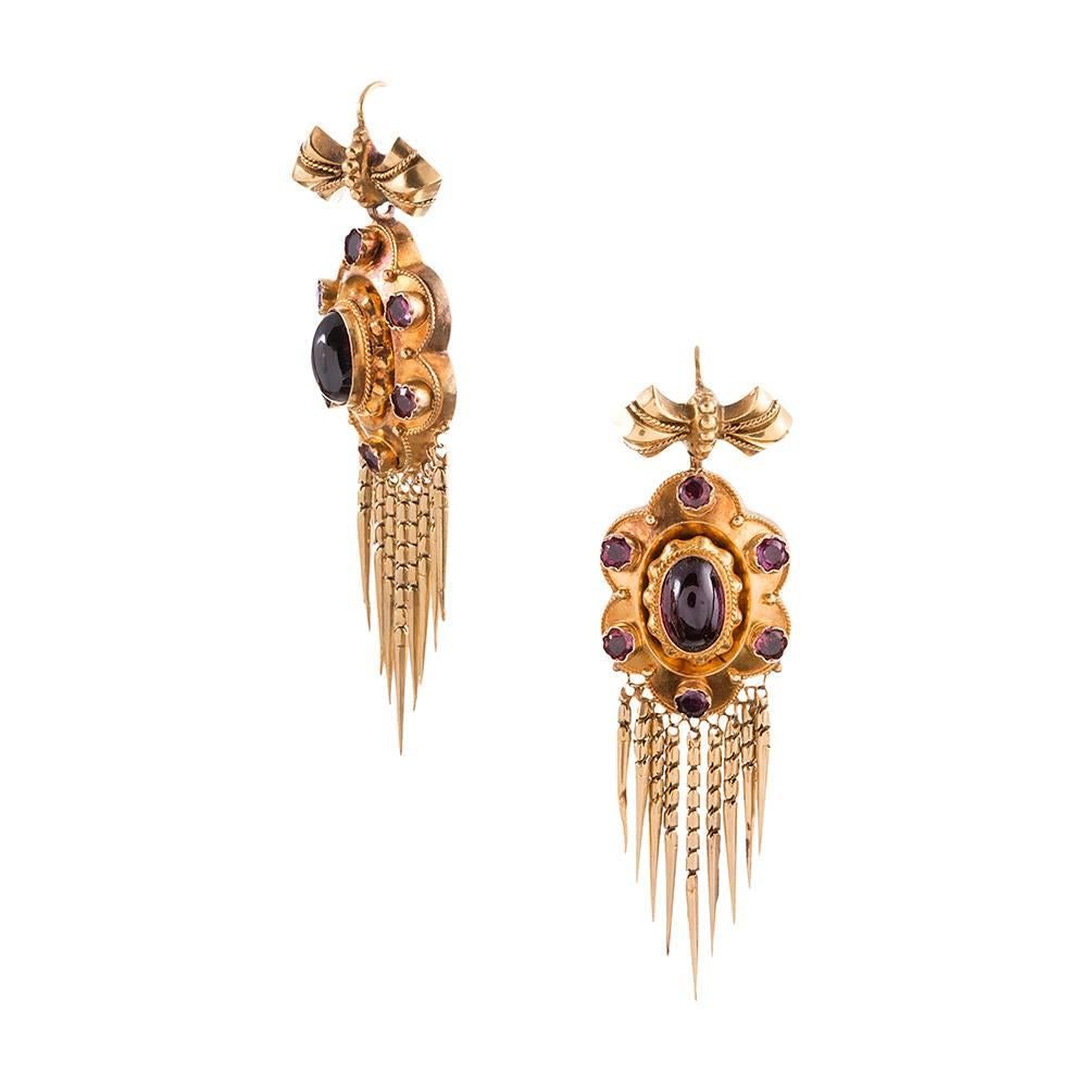 2 inches of Victorian finery rendered in 18 yellow gold with a cluster of cabochon garnets augmented by bearded bottoms and suspended from a golden bow. 