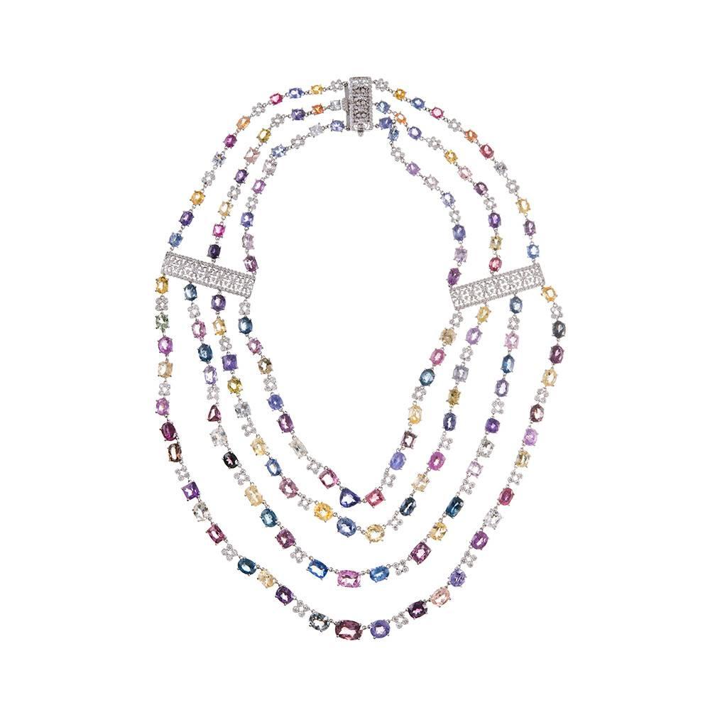 18 karat white gold necklace set with a glorious array of faceted round- and oval brilliant sapphires, displaying the rainbow of hues in which sapphires can come. The front section consists of four strands of alternating colored sapphires and