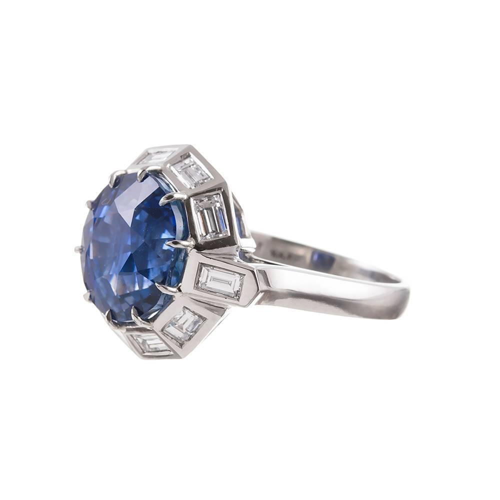 Platinum hand made ring set in the center with a 9.11 carat faceted round sapphire and framed by a halo of bezel set baguette diamonds. This unique creation is an artful interpretation of the classic cluster style. It is even more beautiful in