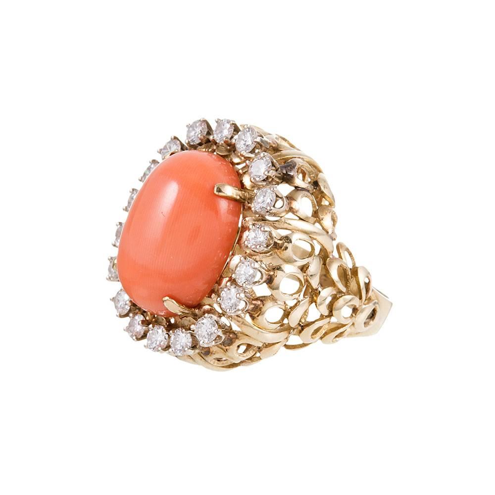 Playful midcentury style abounds with this impressive cocktail ring. The 14k yellow gold mounting is designed as a stacked collection of loops, a repeating pattern that reinforces the midcentury charm. The large coral cabochon is framed in a single