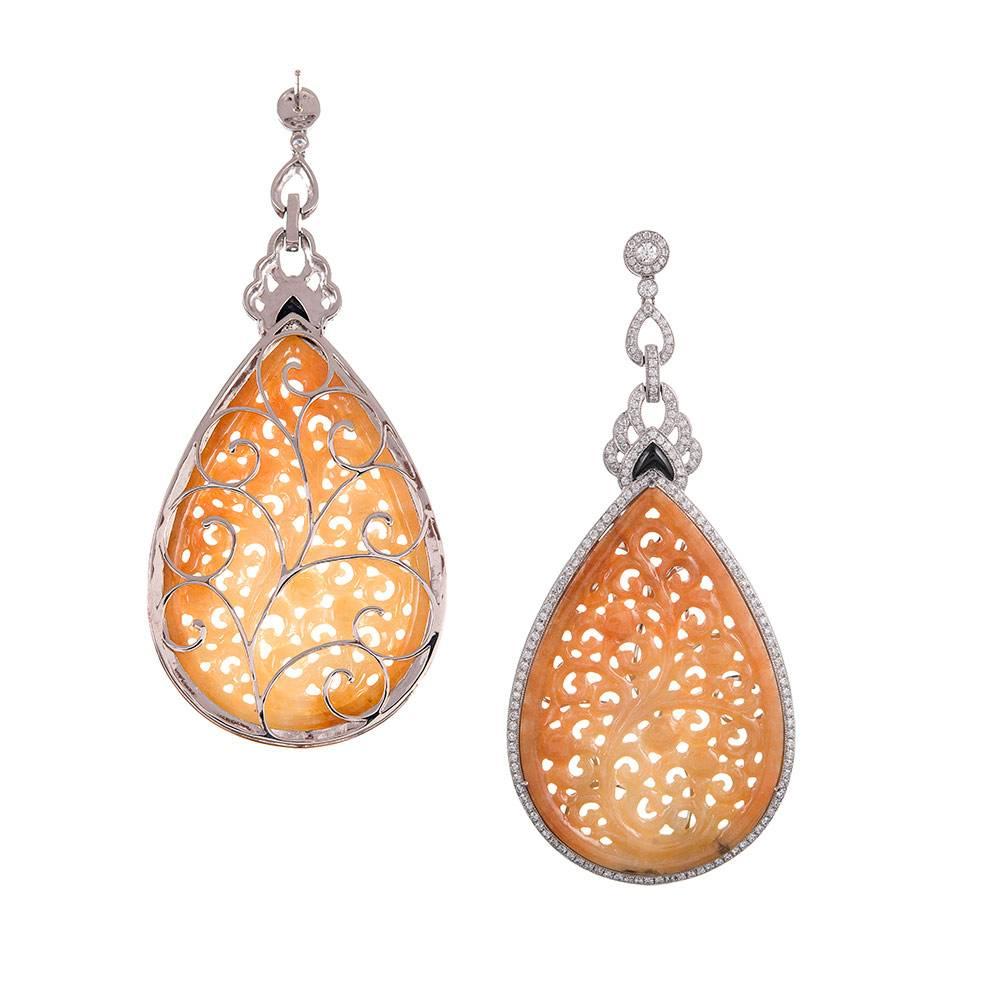 Elegant earrings made of carved orange jade that is accented with a frame and intricate drop of brilliant diamonds and a hint of onyx. The jade weighs 12.47 carats while the diamonds weigh .71 carats and grade as G-H color and Vs2-Si1 clarity. These