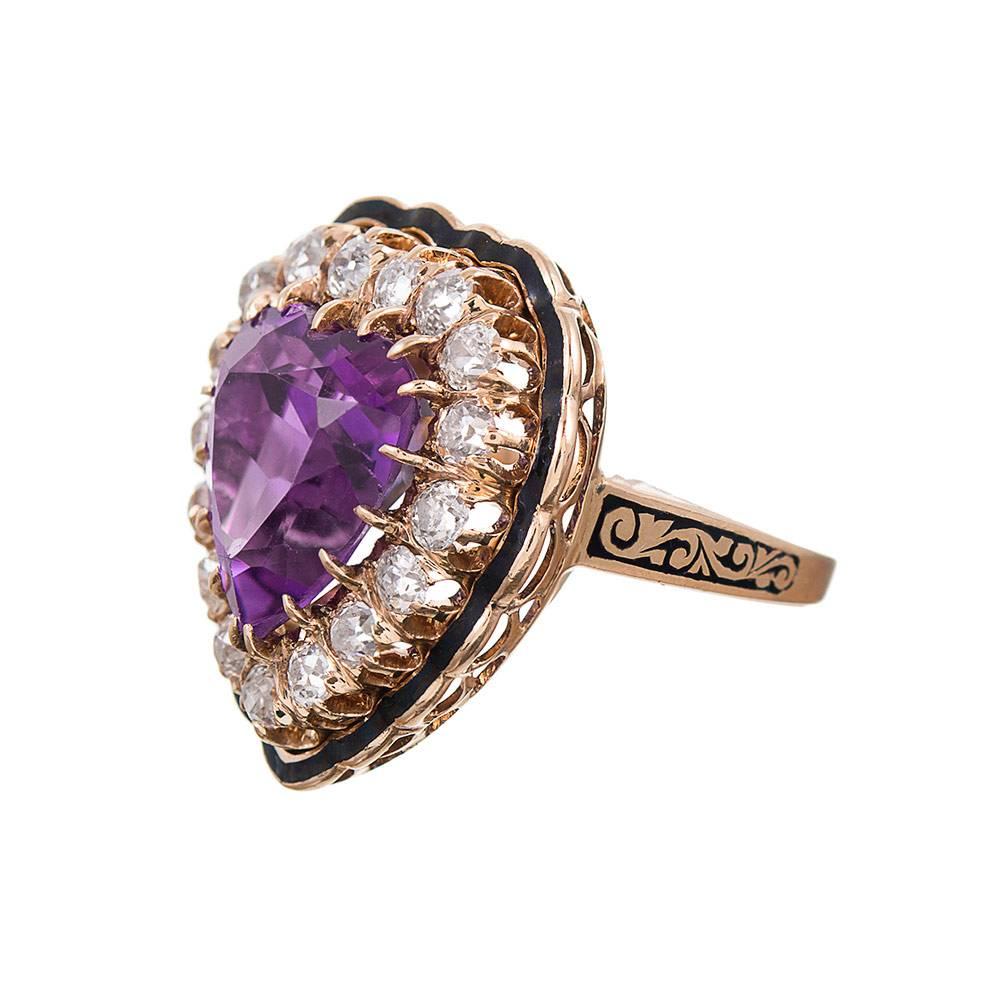A playful bit of antique finery, the centerpiece a 9.08 carat heart-shaped amethyst, which is framed by 1.50 carats of brilliant diamonds and accented by black enamel. The 14k yellow gold mounting is currently finger size 7, however, this can be
