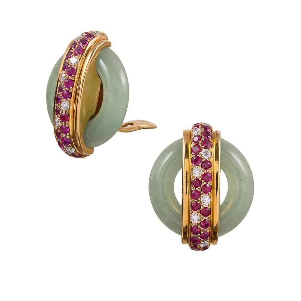 Stunning and sophisticated earrings made of smooth jade discs, decorated with an intersection of polished gold and set with brilliant diamonds and rubies. The diamonds weigh approximately 1 carat in total. Double signed 