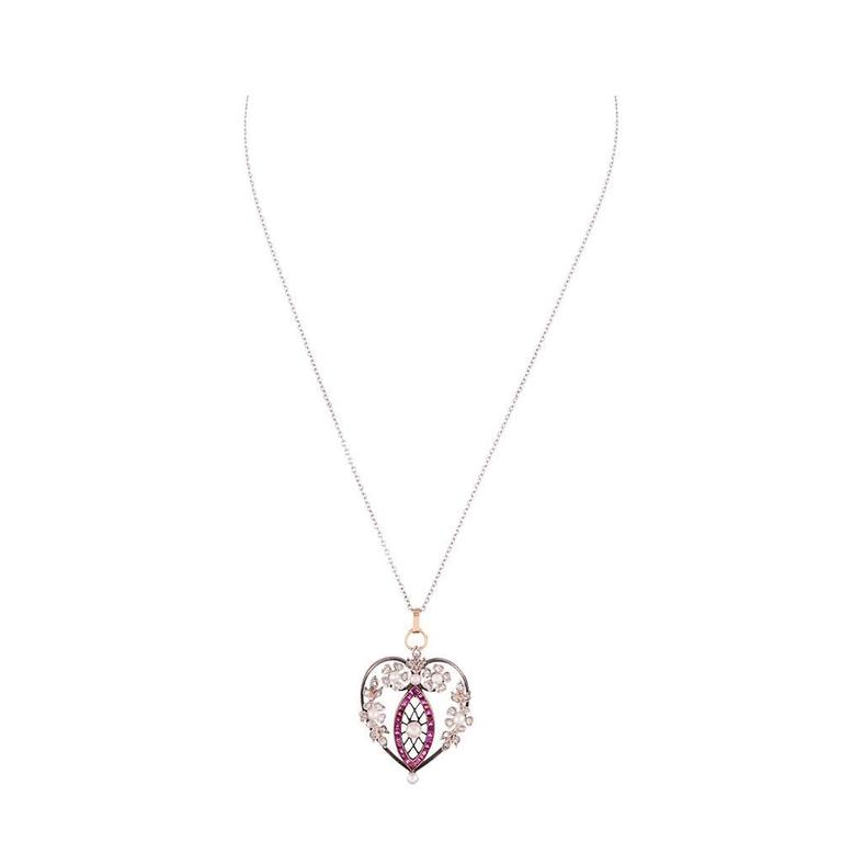 Silver over yellow gold pendant decorated with twenty-seven rubies, thirty-four diamonds and seven pearls, artfully assembled to create a heart shaped adornment with feminine and distinctly antique charm. The pendant measures 1.75 by 1 inch