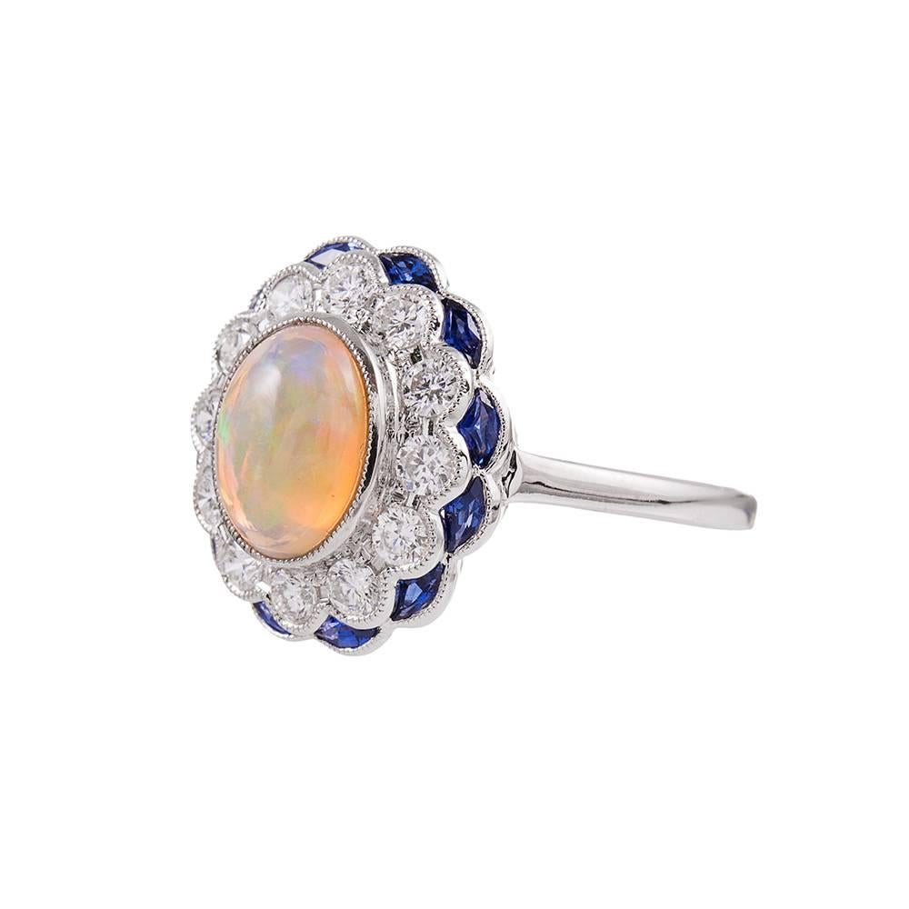 A classic cluster ring with an uncommon combination of gemstones: a 2 carat opal cabochon its in the center of a scalloped frame of brilliant round diamonds (1.02 carats total) and custom-cut blue sapphires. It’s gorgeous! Although this ring