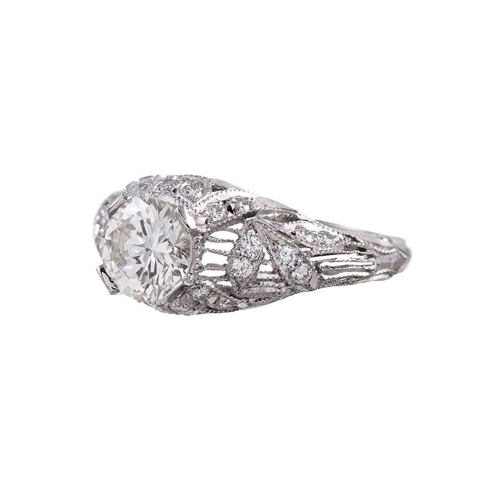 Sweeping strokes of platinum wire accented with brilliant diamonds and millgrain edges create a gorgeous setting for a center round diamond. Look closely and wonder if the creator of this ring intended for it to look like bamboo shoots and leaves.