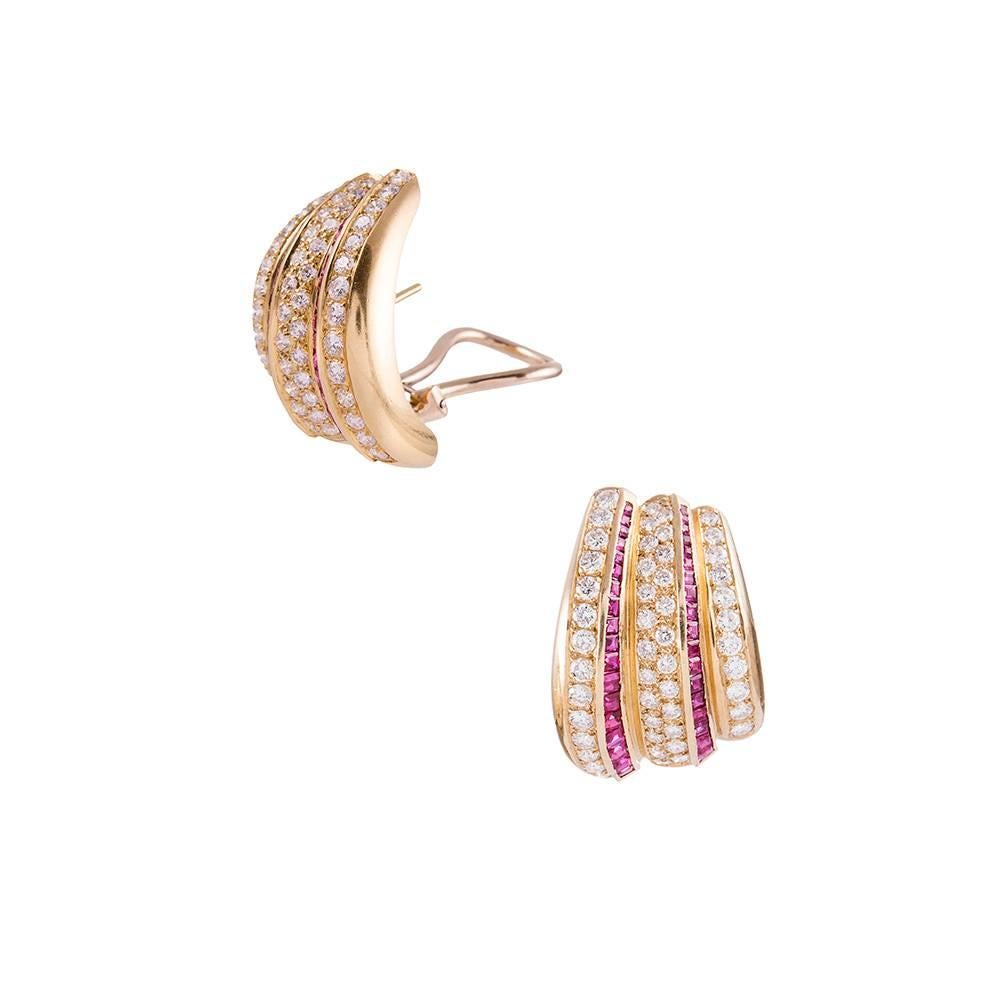 Retro style elements translated into late 20th century design... Intense red rubies and brilliant white diamonds dazzle on stripes of 18k yellow gold and are fashioned into a modified hoop design. 1 ¼ inches tall by 7/8 of an inch wide and finished