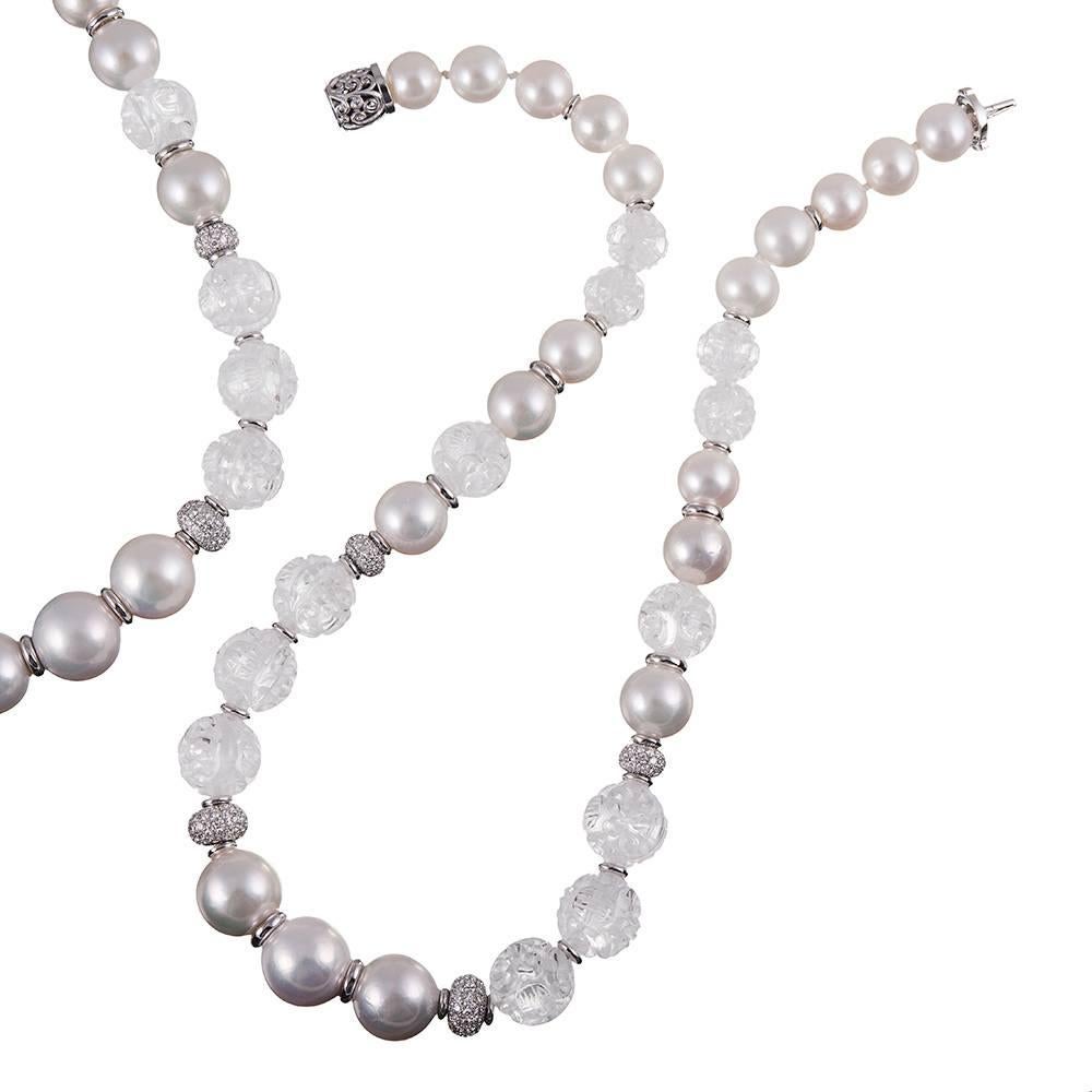 A 19 inch strand of lustrous round white freshwater pearls is intersected with carved rock crystal orbs flanked by white gold and diamond laced rondelles and capped with a carved white gold clasp. Part of the 