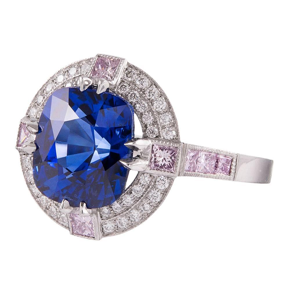 Stunning custom made platinum ring with a faceted round sapphire weighing 4.33 carats set in the center. The intense color of the stone is striking and beautiful. Look closely to notice the pink and white diamonds framing the stone and decorating