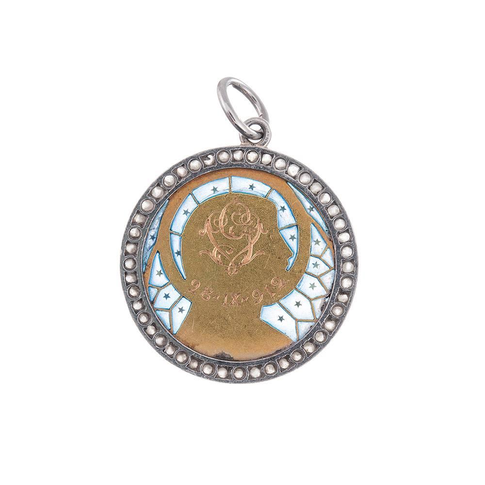A charming adornment, measuring 7/8 of an inch in diameter and depicting the Madonna adorned with a golden halo and surrounded by blue plique a jour enamel. The outer frame of rose cut diamonds is a lovely compliment to this platinum and 18k yellow