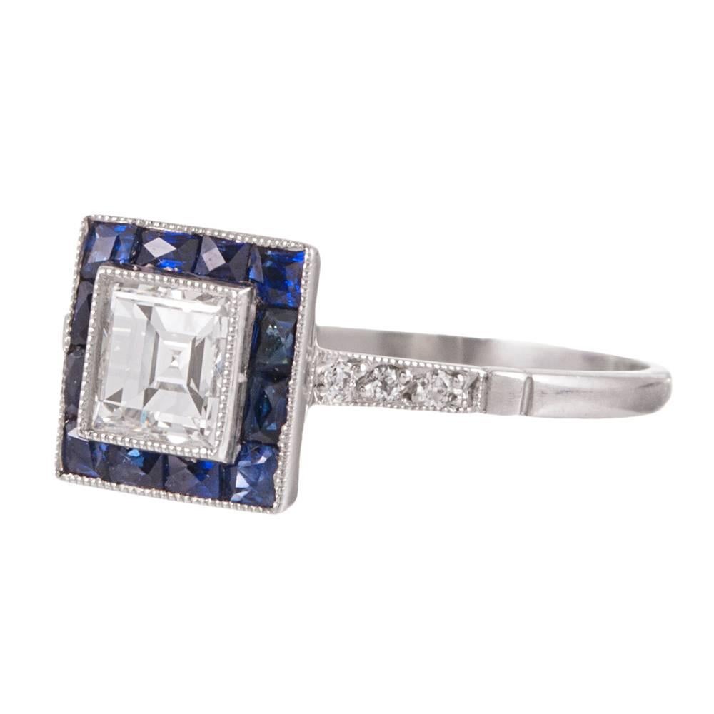 Created in the classic art deco style, yet of more modern age, this sweet platinum ring has a .47 carat princess cut diamond center, framed with a border of blue sapphires and accented with diamonds on the shoulders. The major diamond grades G/Vs1.