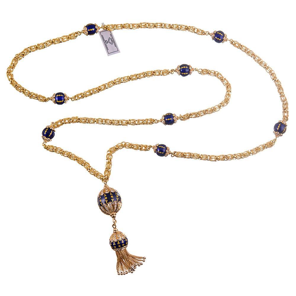 Made by hand of 22- and 18 karat yellow gold, the stylized chain measures 35 inches and is decorated with ornate orbs of blue enamel and brilliant diamonds. The tassel drops a further 3 inches. In total, the necklace is set with 245 diamonds that