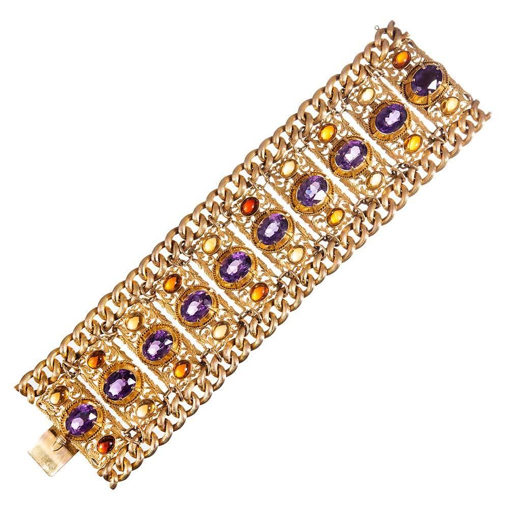 A bold marriage of artistic style, measuring an impressive 2.2 inches wide. The bracelet is made of 18k yellow gold rectangular stations, each set with a large faceted oval amethyst, flanked on both sides with a cabochon citrine and heavily