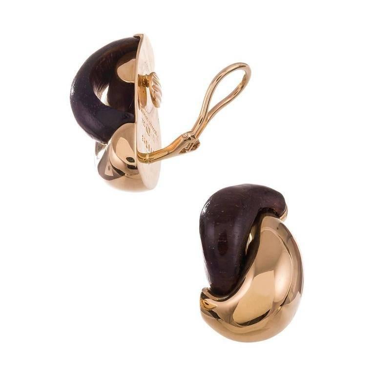 A playful take on a classic hoop design, compliments of iconic American jeweler Seaman Schepps. Sensuously curved rosewood sits nestled symbiotically by a sweeping stroke of 18k yellow gold. 1 1/8 inch tall and 5/8 inch wide. Currently clips,