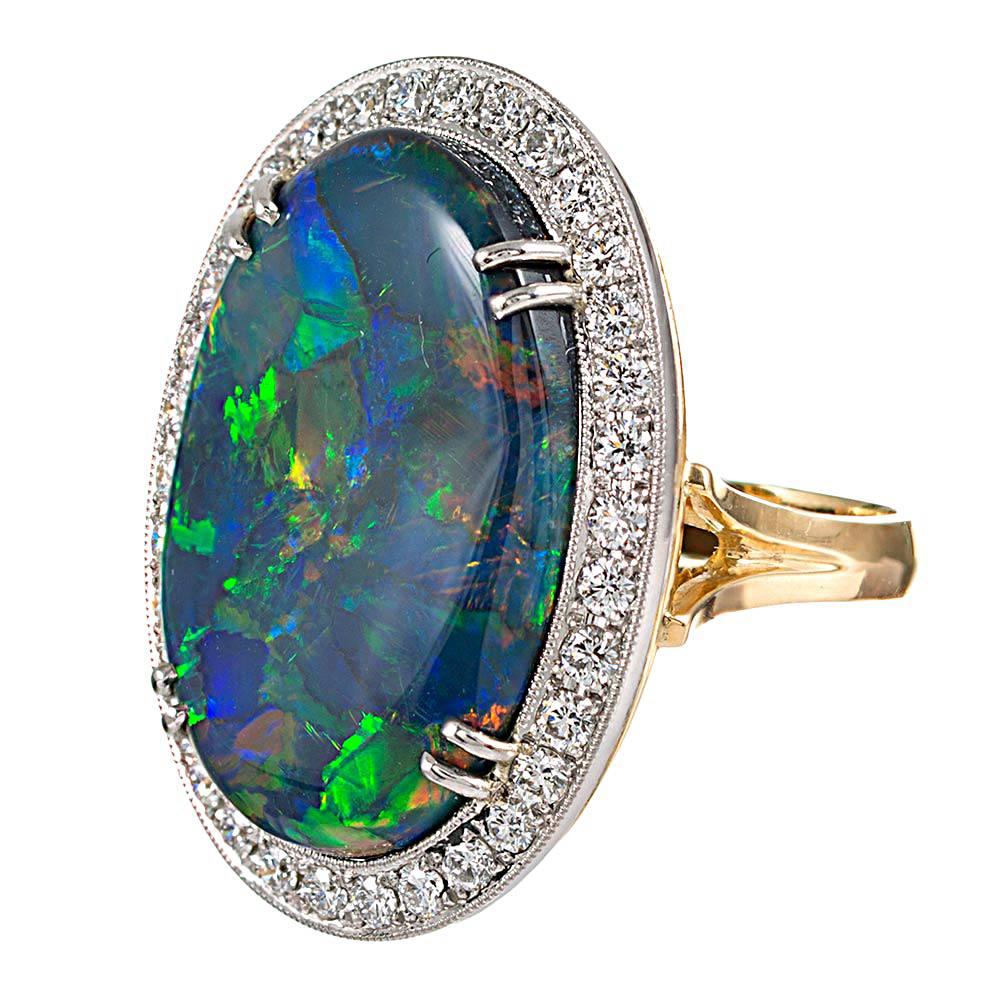 An exceptionally beautiful gem quality opal, with strong flashes of blue, green, orange and red, framed in a bright border of brilliant white diamonds. The back of the stone is clearly visible in the open mounting and as no matrix at all, so the