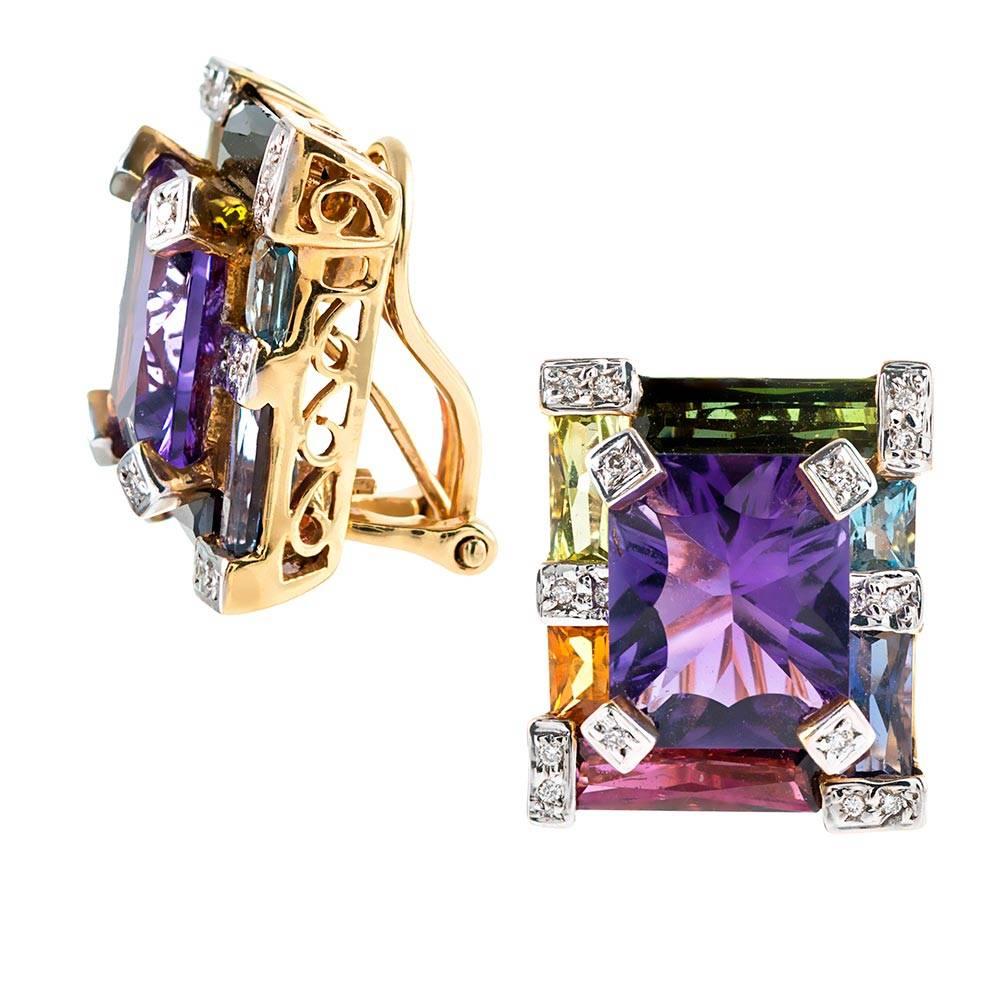 A colorful bounty of assorted gemstones are assembled in symmetrical architecture and mounted in 18k yellow gold. In total, the colored stones weigh 12.10 carats and are accented with .12 carats of white diamonds. Currently clips, a post can be