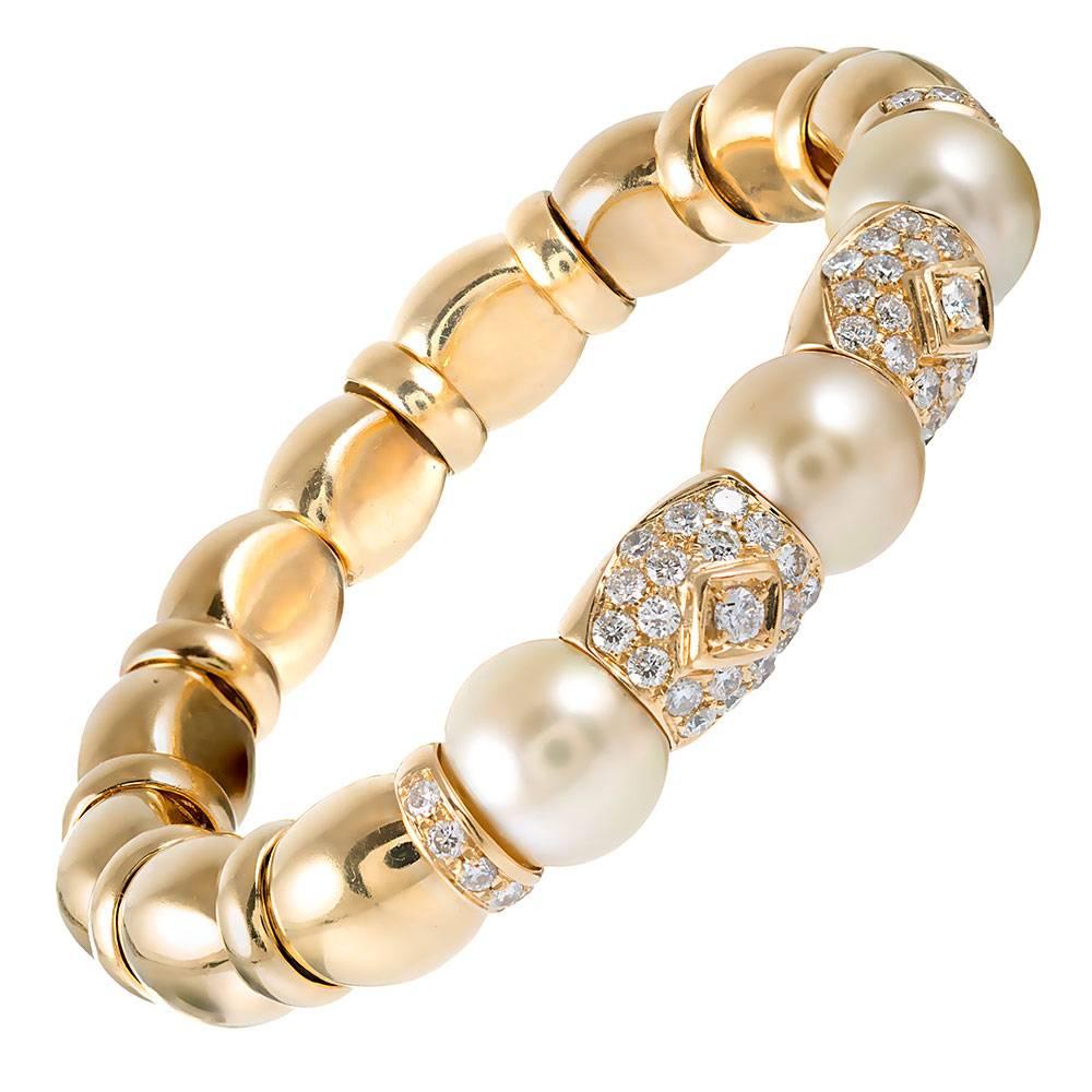 A unique design, decorated with 1.25 carats of brilliant white diamonds and soft golden pearls, the bracelet is rendered in 18 karat yellow gold. Flexible and comfortable, this piece is fashioned without a clasp, yet moves enough to allow you to