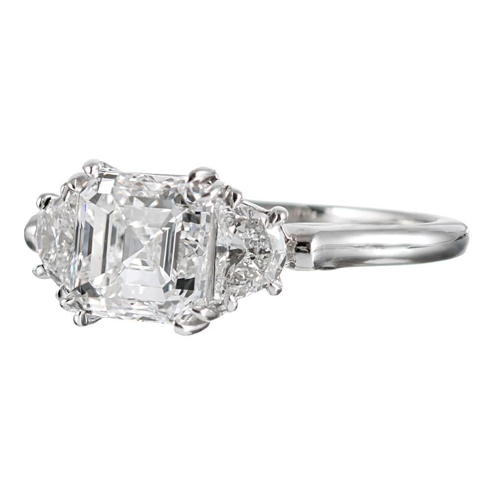 A beautiful treasure for the white diamond enthusiast, this classic three stone diamond ring combines an asscher cut center diamond with a pair of half-moons. GIA describes the 2.01 carat center diamond as exhibiting F color, Vs1 clarity and “triple
