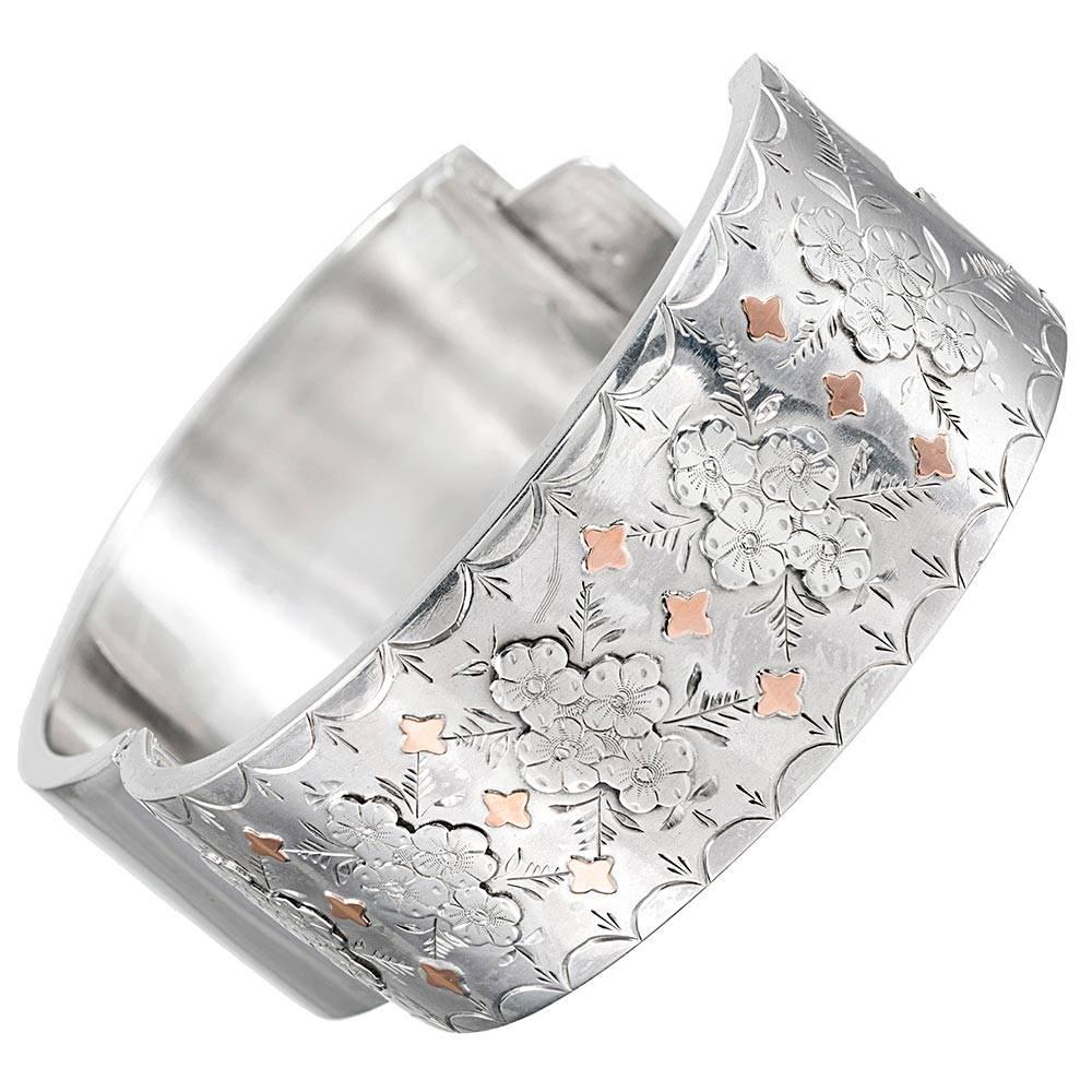 Measuring 1 inch wide and with an interior diameter of 2 1/8 by 2 inches, this classic Victorian bangle is made of silver and accented with rose gold. Note the floral design and beautiful engraving.