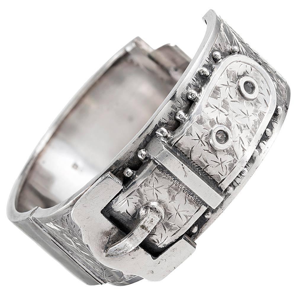 Measuring 1 inch wide and with an interior diameter of 2.25 by 2 inches, this classic Victorian bangle is made of silver and accented with a bold buckle motif. Note beautiful engraving.