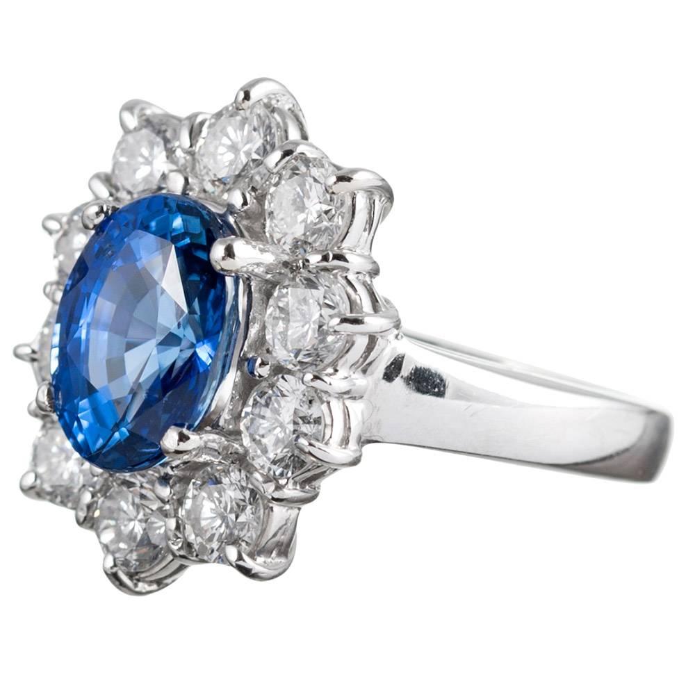 A classic cluster style ring set in the center with a 3.85 carat sapphire and framed by a scalloped border of 1.60 carats of brilliant diamonds. The sapphire is GIA-certified “No heat” and of Sri Lankan origin. The diamonds grade as G-H color and