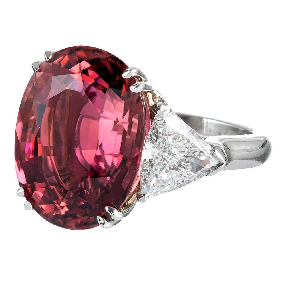 A classic beauty, rendered in platinum and 18 karat yellow gold. The center oval brilliant pink tourmaline weighs an impressive 17.06 carats and is flanked by a pair of white trillion diamonds that weigh 2.56 carats combined. The ring has striking