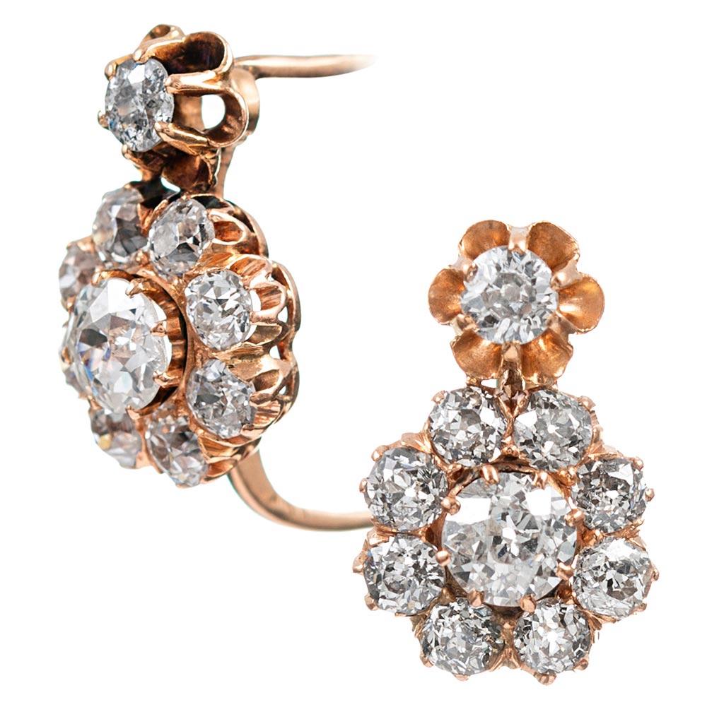 Charming clusters of old European brilliant cut diamonds are suspended from a single stone set in the center of a flowerlike mounting. The earrings are made of 18 karat rose gold and are estimated to have been created circa 1890. In total, there are