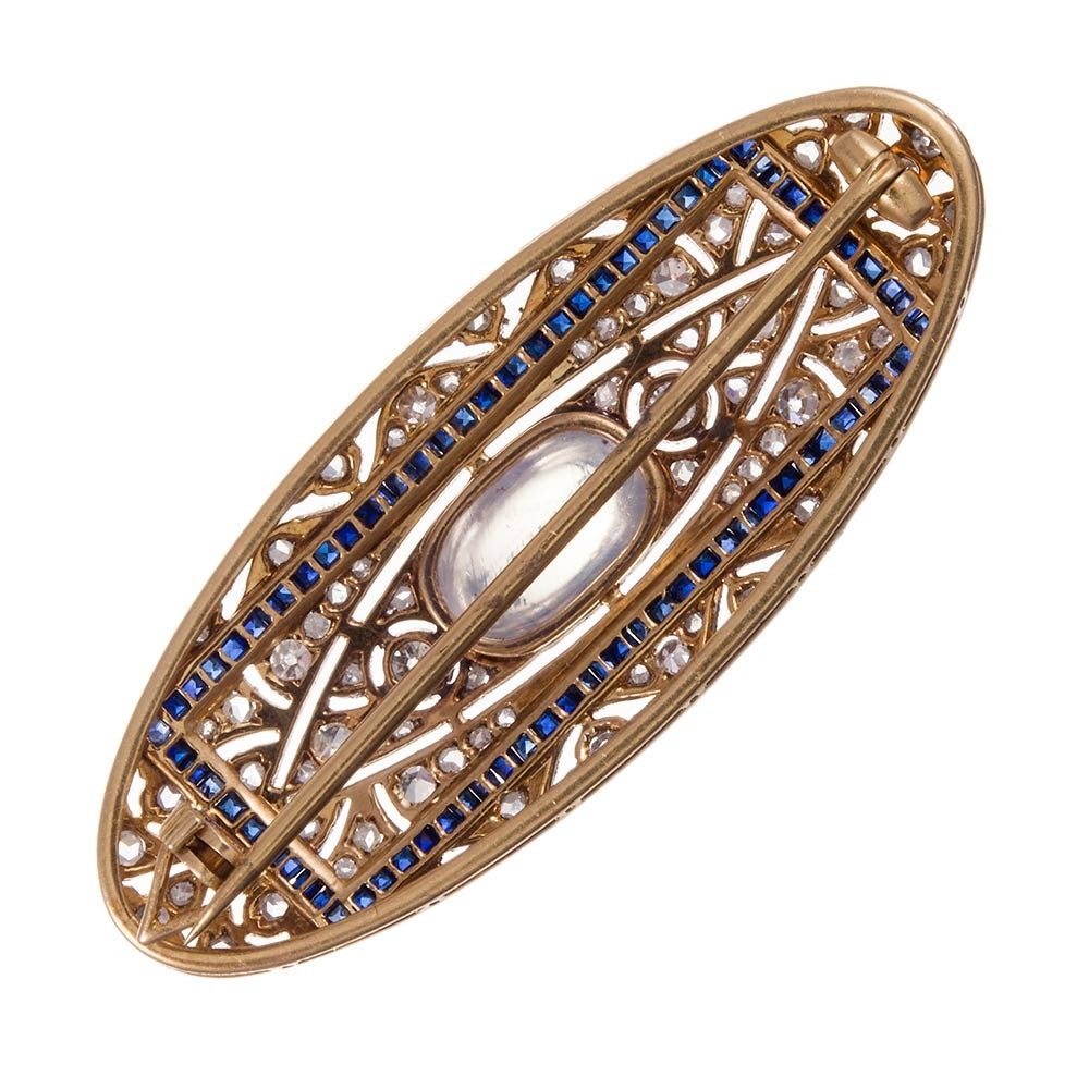 Classically styled Edwardian brooch, rendered in platinum over yellow
gold. The center is set with a blue flash cabochon moonstone, its
mystical color enhanced by a rectangular frame of sapphires and brightened
by brilliant diamonds. It measures