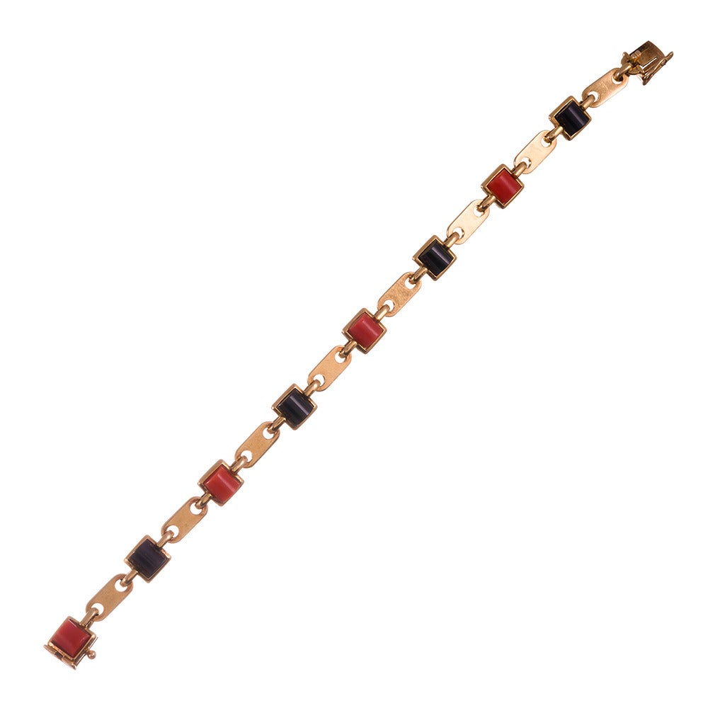 18k yellow gold bracelet, designed as an oval-shaped link, connected by
alternating coral- and onyx-set rounds. The stones look like a halved
cross-section of a tube. This is architecturally interesting and the
appeal is heightened by the