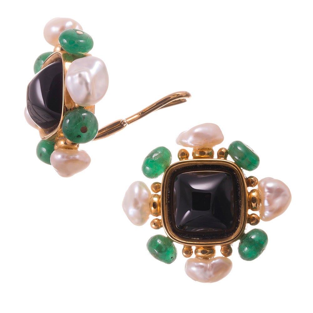 Signed Trianon and offering a chic color combination of gemstones with a
sugarloaf onyx centerpiece, framed in a sunburst pattern of Biwa pearls
and emerald beads. Golden roundels add depth and a warm glow from the
background. The absence of