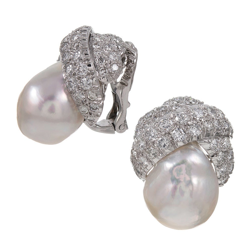 Stunning, substantial and sophisticated David Webb earrings made of platinum and 18k white gold. The lustrous baroque pearls measure 14 x 19 and 15 x 19 millimeters and are a gorgeous pair. They are partially enrobed in a loosely-knotted ribbon of