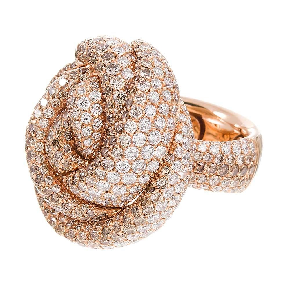 Undulating strands of diamonds form a knot design, similar to a rosette, of brilliant white and chocolate diamonds, 8.35 carats in total. The diamonds continue down the shoulders of the wide shank. This ring substantial in its design, materials and