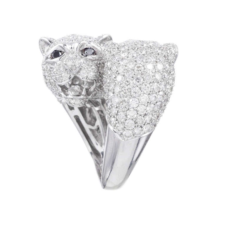 8.92 carats of (G/Vs) brilliant white diamonds have been meticulously set to crete this fantastic bypass style ring. The opposing heads of two panthers, their mouths agape, fangs bared, tongue showing and eyes set with black diamonds, have been