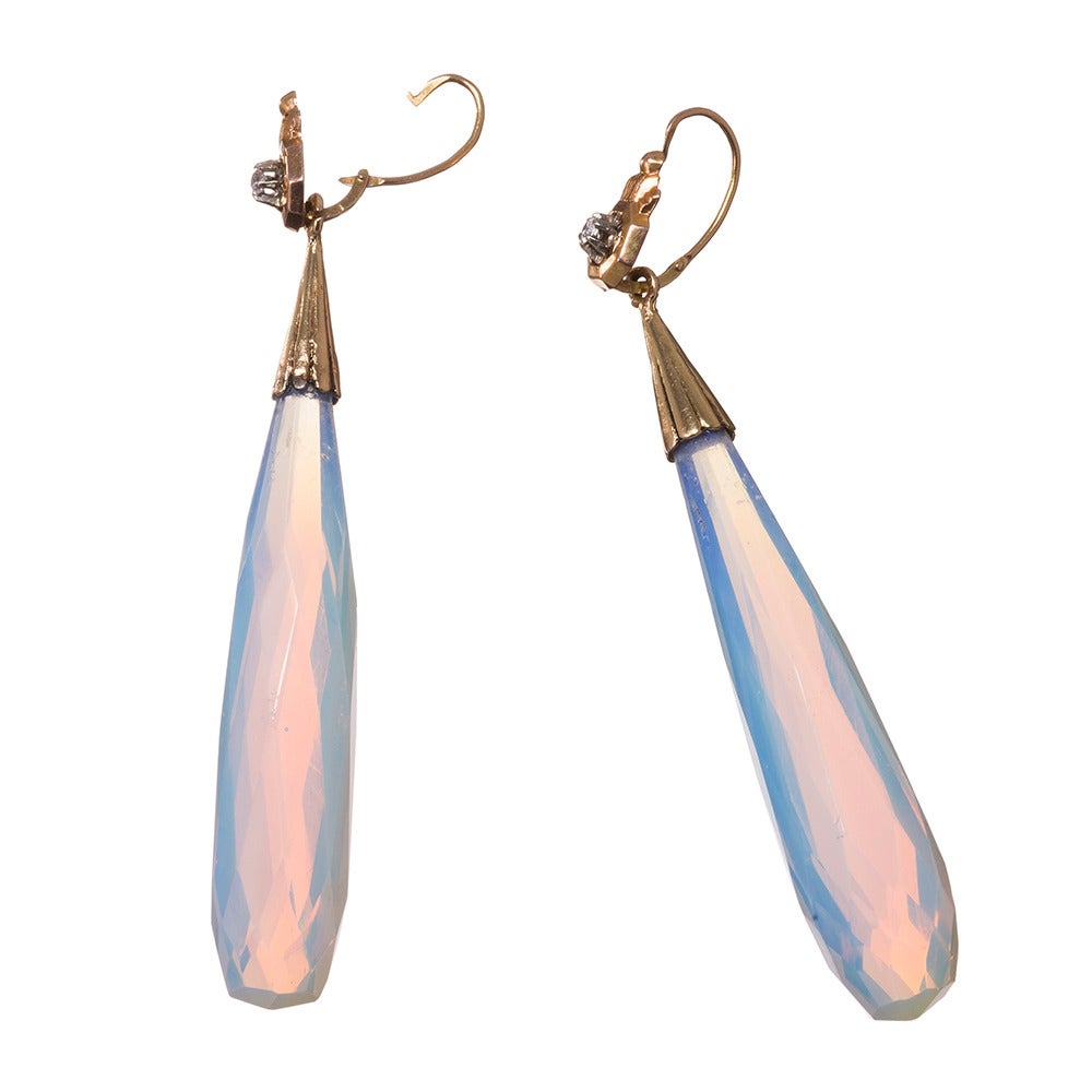 Striking and feminine earrings with a dramatic nearly three inch length. The tops are delicate and stylized, made of 18k yellow gold and each set with a single diamond. The opaline glass looks like faceted opal. It catches the light playfully and