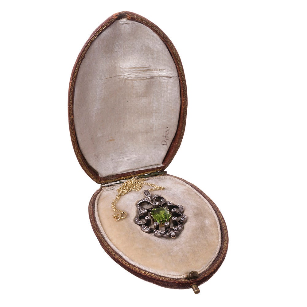 Made of Silver over 15k yellow gold and set with a peridot center stone, surrounded by a scalloped frame of old European cut diamonds. The pendant measures 1.5 inches long and 1 inch wide. Peridot looks well with nearly any color story and is
