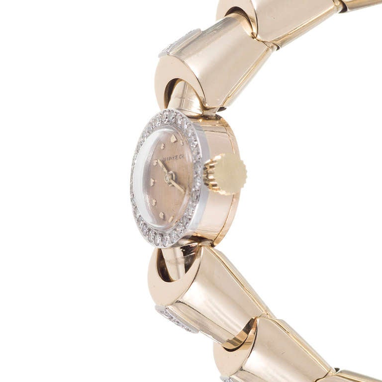 Tiffany & Co lady's 14k yellow gold manual-wind bracelet watch with a 17-jewel Concord movement. With a diamond bezel and diamonds on some of the bracelet links, this piece is just dramatic enough to stand up to formal attire, yet can also be worn