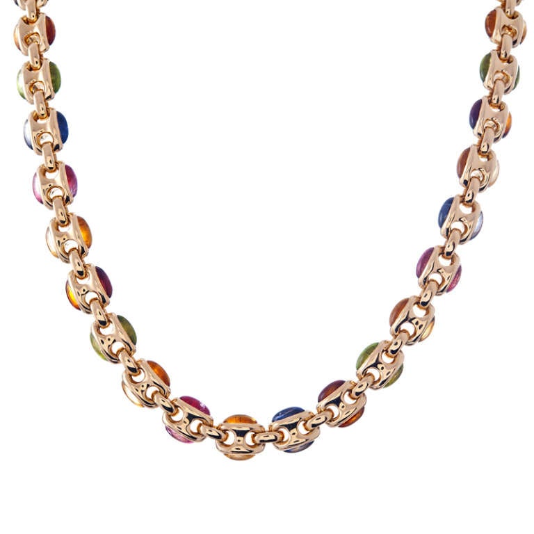 Measuring approximately 19 inches in overall length, this striking necklace has a unique design which appears to be inspired by Bulgari's iconic creations. The sides of each domed 18k yellow gold oval link are set with assorted precious- and