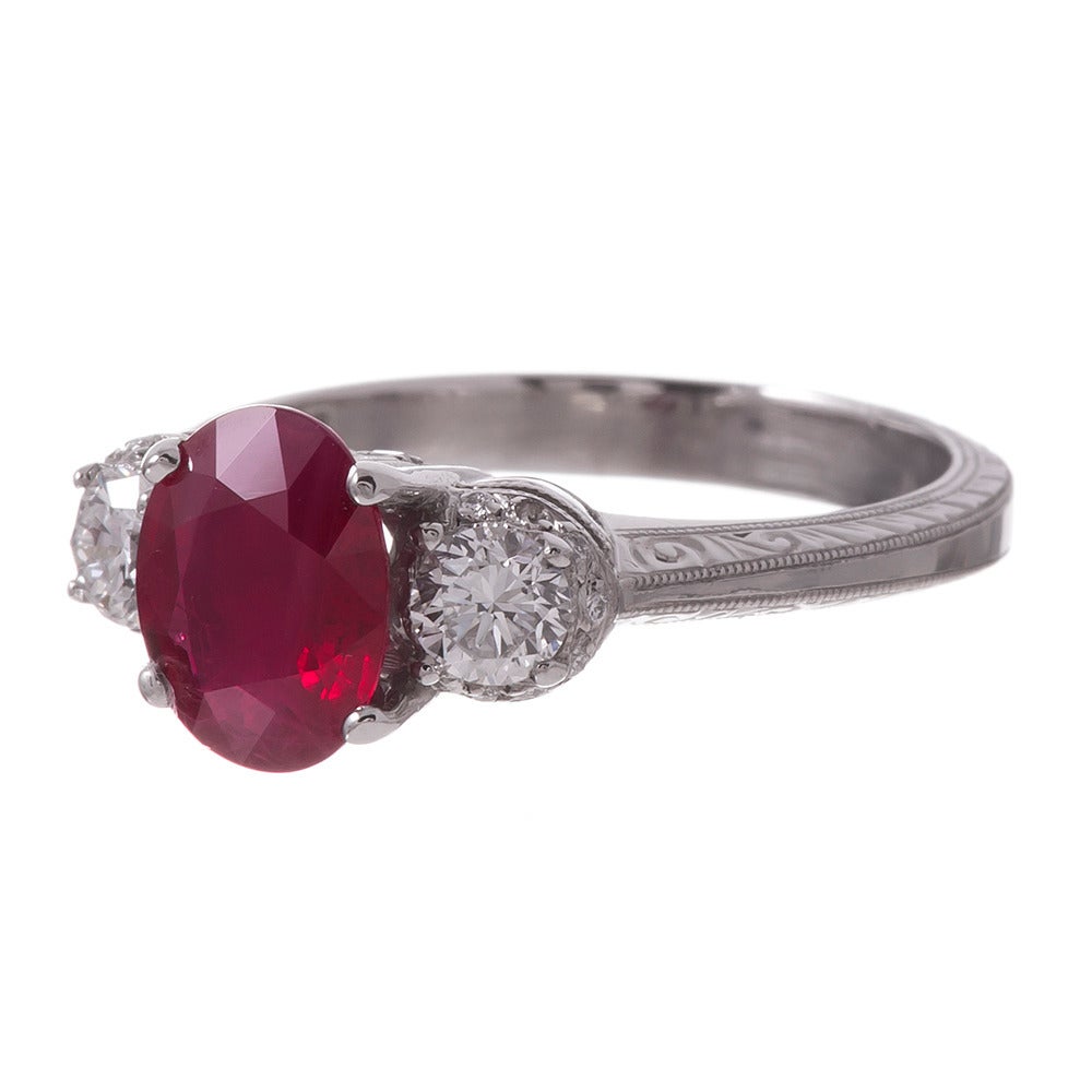 Platinum ring made by Tacori, finely detailed accents and precision styling. The center stone is a 1.78 carat oval ruby with intense, true red color. It is flanked by a pair of round diamonds that weigh .47 carats combined. Tacori is esteemed for