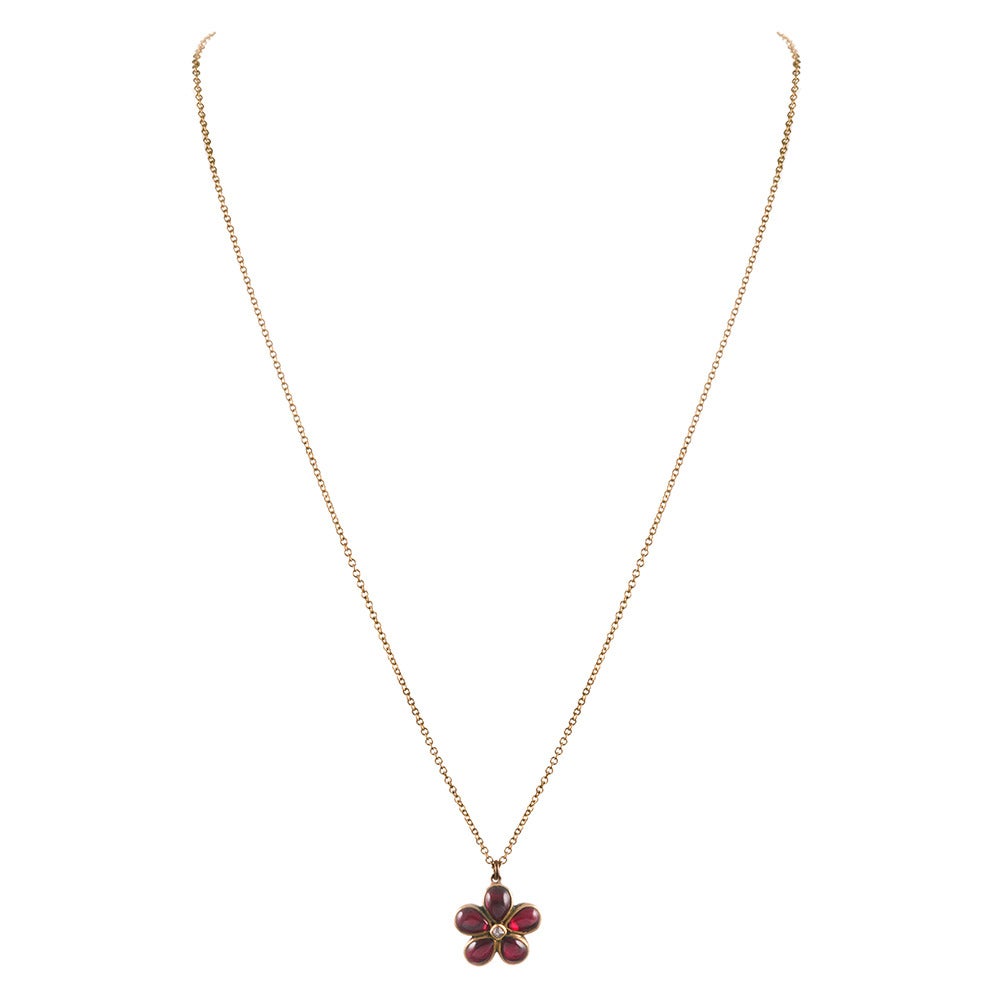 Charming little suite of earrings and a pendant, flower shapes made of cabochon garnets, set in the center with a diamond and rendered in 9 carat rose gold. The chain for the pendant is new. Each flower measures approximately a half inch in