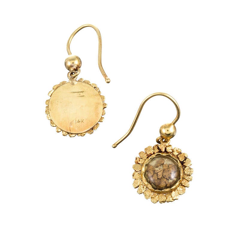 Charming turn of the century gold nugget earrings, made of 14k yellow gold. Measuring 1 inch in length, including the ear wire, and a half inch wide, these dainty dangles consist of a frame of flattened gold nuggets surrounding a 