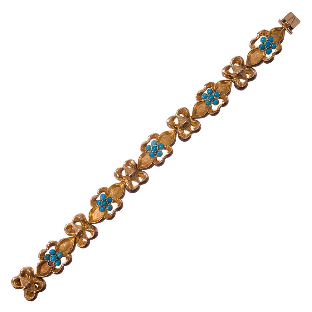 A late Victorian bracelet comprised of ornate links of high-polished and satin-finished gold, speckled with florets of turquoise cabochon clusters. 15k yellow gold indicates this was made in the UK. The bracelet measures 6.5 inches in overall