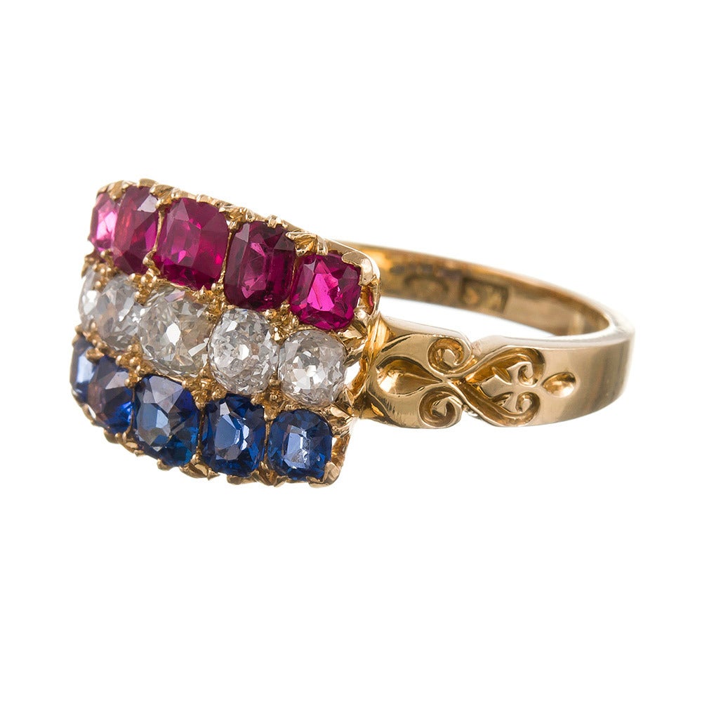 A lovely plaque ring with red, white and blue stripes of rubies, diamonds and sapphires, set in 18k yellow gold, a lovely nod to Americana. 1.50 carats each of sapphires and rubies and 1.25 carats of diamonds. Beautiful engraved detail on the sides