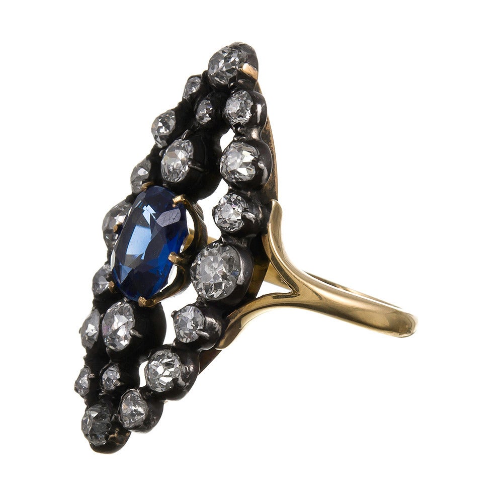 A Marquis-shaped open plaque ring, set in the center with a 2.50 carat sapphire and framed in a lacework pattern of 3 carats of old European cut diamonds. The sapphire is true cornflower blue color- soft and vibrant. Set in silver over 18k yellow