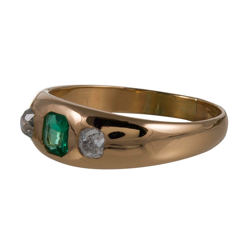 18k yellow gold ring with a full compliment of English hallmarks inside. Classic gypsy style, set with a .50 carat emerald and flanked by a  pair of old European cut diamonds that weigh .50 carats combined. Suitable for a lady or a gentleman. Size