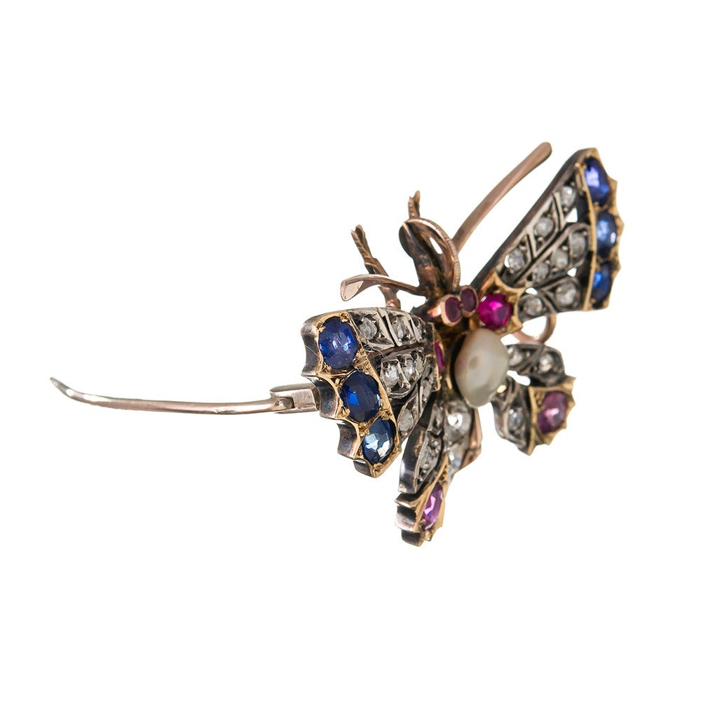 Crafted of silver and 18k yellow gold, set with a symmetrical pattern of diamonds, sapphires and rubies and anchored in the center by a pearl. Approximately 1 carat of diamonds, plus 2 carats each of sapphires and rubies. 1.75 by 1.25 inches and