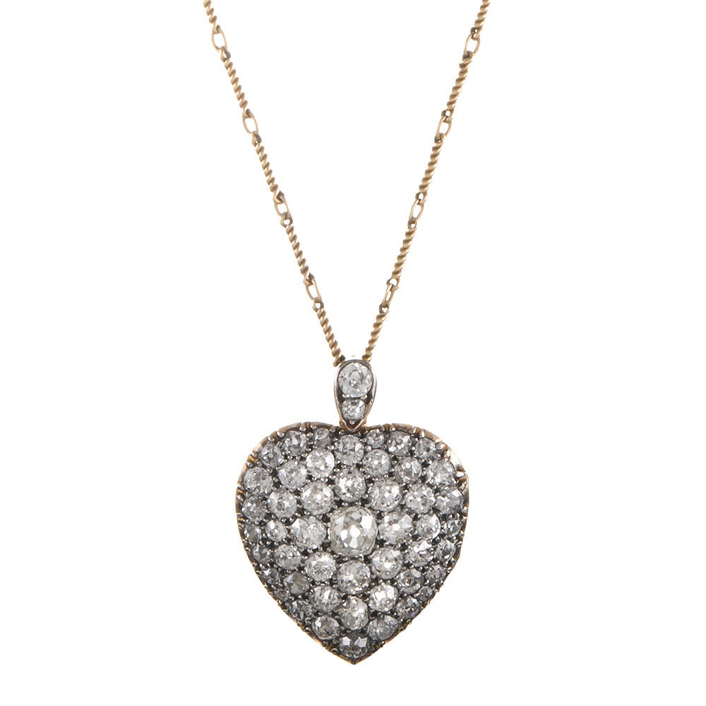 A cluster of approximately 4 carats of old European cut diamonds, fashioned into a heart shape and suspended from an antique chain. The pendant has a glass locket back, so you may subtly display your devotion to your beloved. The pendant measures