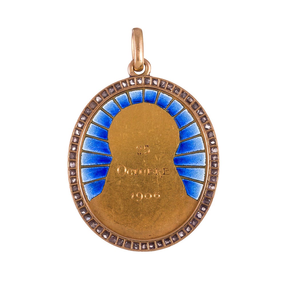 An incredibly beautiful expression of religious devotion, rendered in 18k yellow gold with rich blue plique-a-jour enamel and a frame of rose cut diamonds. At the center, Madonna is framed in a golden halo, with enamel sunbeams radiating from behind
