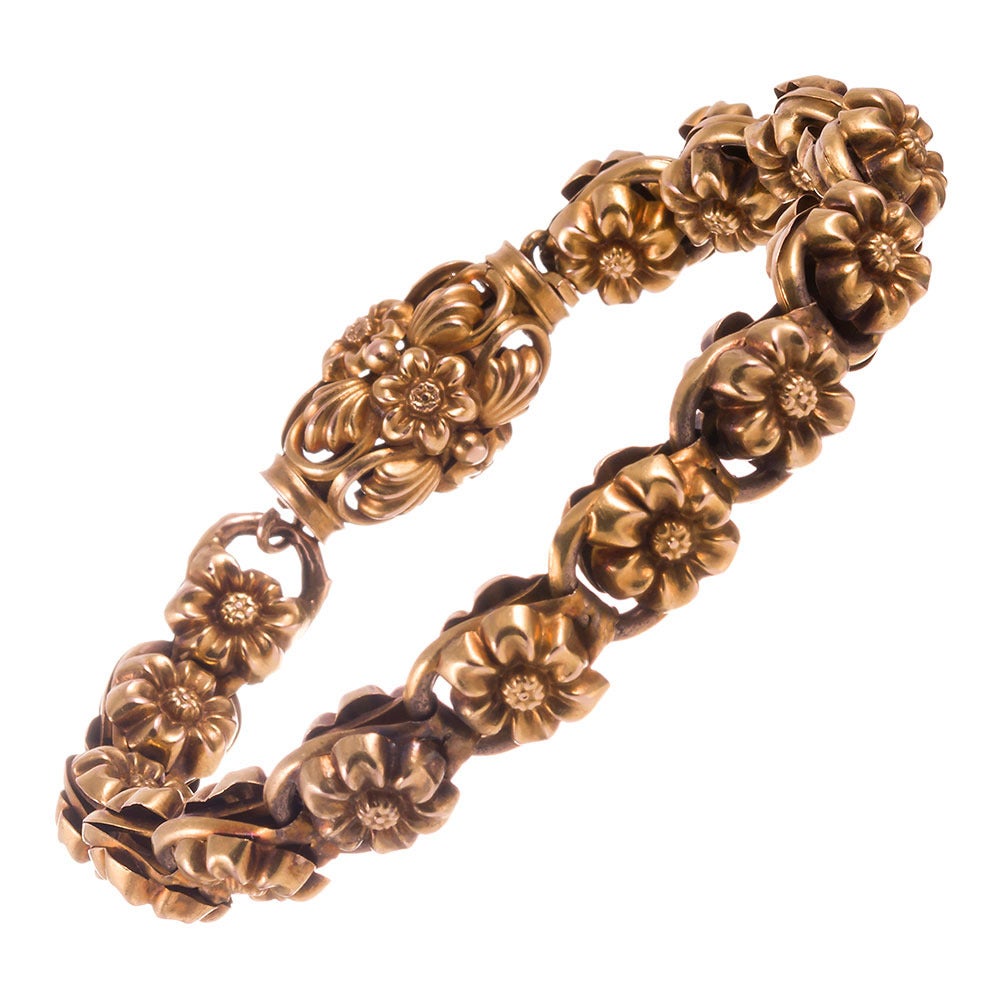A repeating pattern of three dimensional golden flowers, linked together and finished with a barrel clasp. Perfect for a summer garden party! 8 inches in overall length, rendered in 18k yellow gold.
