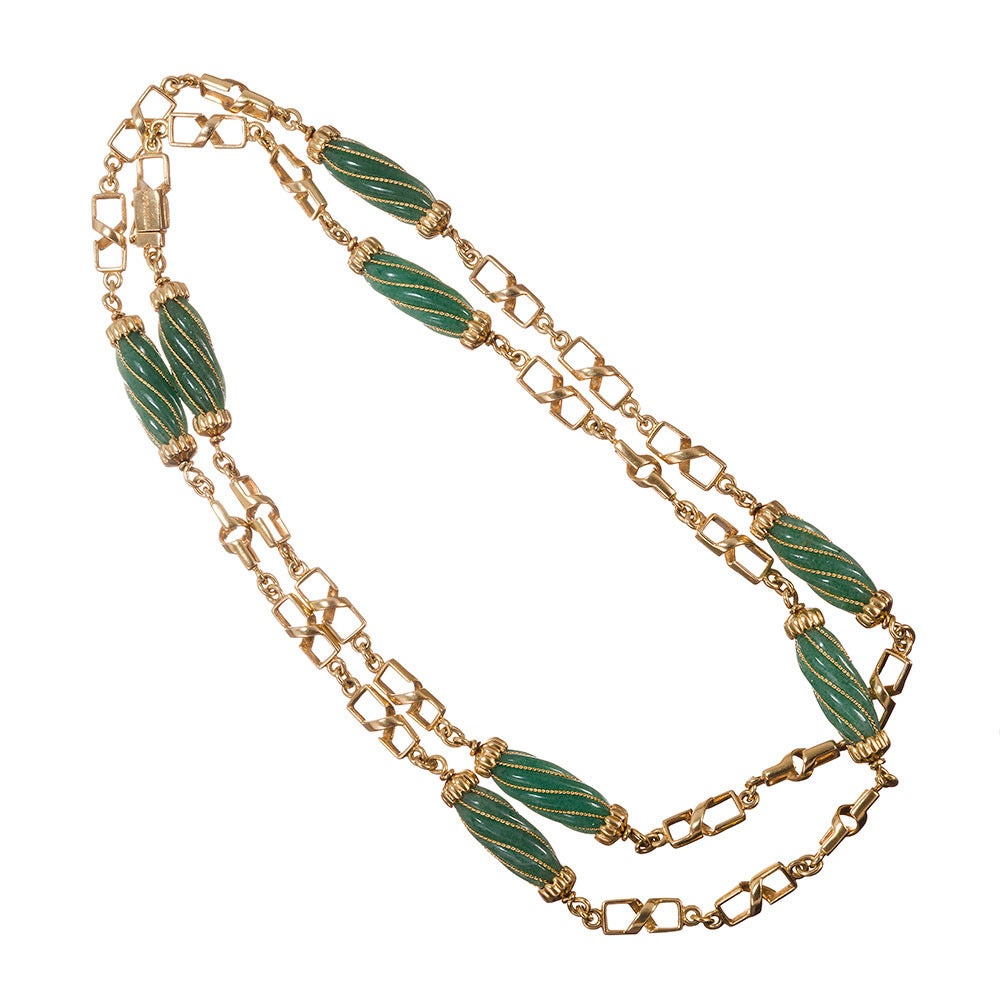 A 32 inch strand of three-dimensional links, rectangular design with a spiral center feature, connecting eight jade barrels. Each section of jade is contained by a clawed golden cap and decorated with strands of gold. Made of 18k yellow gold and